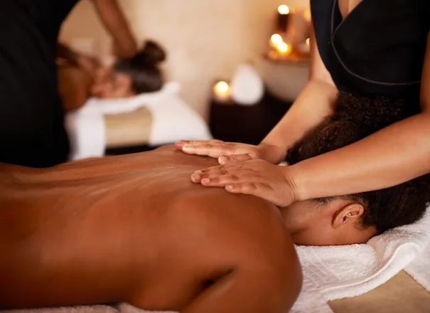 Two guests receiving massage treatments side by side in a candlelit spa room