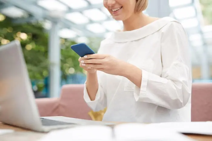 A guest smiling while booking a spa appointment on her phone